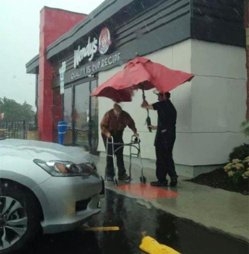 Nhân viên tại cửa hàng này đã tháo cả chiếc dù vốn gắn trên bàn để đến che mưa cho một cụ già.